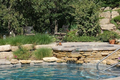 A dark-bottomed pool creates a pond-like feel. The natural stone was mined on site. The pavers are Unilock Brussels Block.