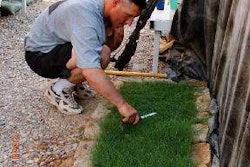 Warrant Officer 1 Brook Turner tending to a plot of grass with a pair of scissors. Photo: Snopes