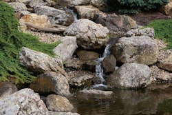 Water features are a staple in the Virginia area, including this waterfall constructed with natural boulders flowing into a koi pond.