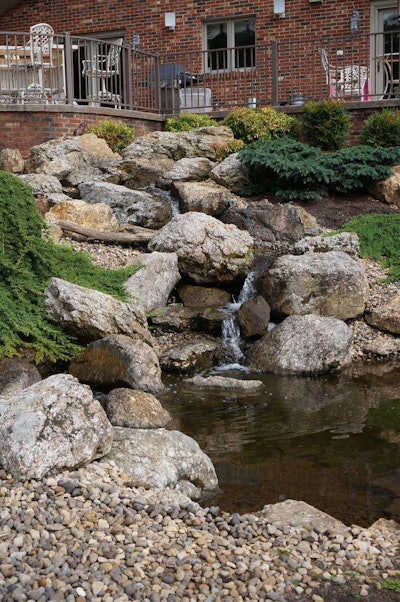 Water features are a staple in the Virginia area, including this waterfall constructed with natural boulders flowing into a koi pond.