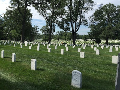 One of the many landscaping volunteers mows between the headstones at Arlington National Cemetery. Photo: David Rountree