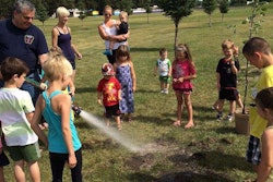 Children help plant an edible garden in a local park, including apple trees. Photo: Partners to End Poverty