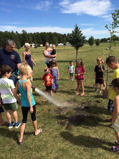 Children help plant an edible garden in a local park, including apple trees. Photo: Partners to End Poverty