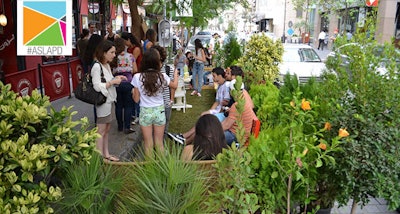 In this shot from a previous year’s Park(ing) Day observance, volunteers talk with passersby who stop to see the miniature park. Photo: American Society of Landscape Architects