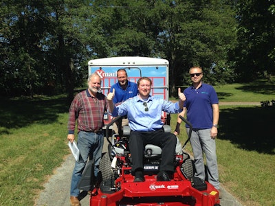 Walt Arnett is in the driver’s seat, with his Dad smiling alongside him, as Exmark representatives deliver his grand prize, the Exmark Lazer Z X-Series mower valued at more than $12,000. Photo: Exmark