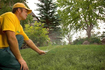 A Grounds Guys worker adjusts sprinkler heads in an irrigation system. Photo: The Grounds Guys