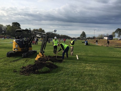 A volunteer from John Deere measures a hole dug by student landscaper Tyler Stefancin of Cuyahoga Community College in Cleveland, Ohio, in the compact excavator competition. Photo: David Rountree