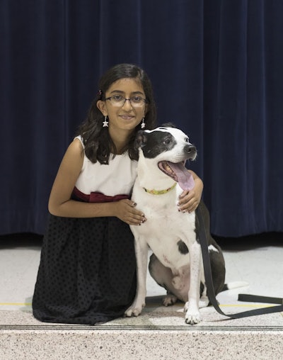 Kashvi Ramani, a fourth-grader at Belmont Station Elementary School in Ashburn, Virginia, poses with Lucky, the rescue dog who inspired the TurfMutt cartoon character.