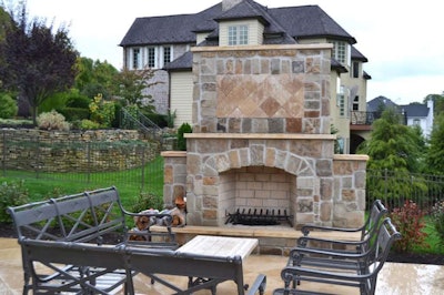This outdoor fireplace was built of natural stone and decorated with a travertine mosaic inlay to create a one-of-a-kind look. Photo courtesy of RTK Design Group