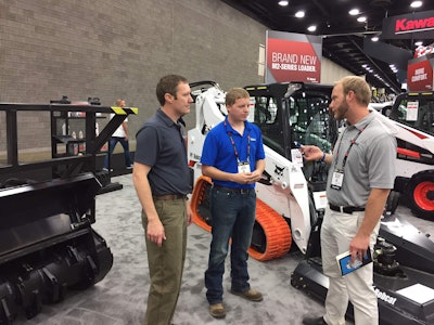 Bobcat’s Eric Dahl, center, talks with colleagues while manning the company’s indoor booth at GIE+EXPO this week. Photo: David Rountree