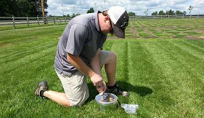 Quincy Law of Purdue University collects greenhouse gas samples from turf plots using a vented flux chamber. Photo: Jon Trappe.