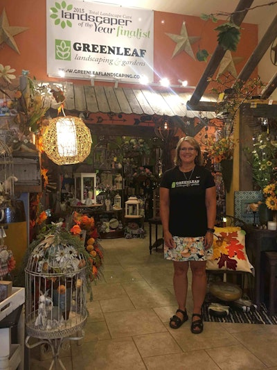 Owner Dorene Schuster stands by her TLC Landscaper of the Year finalist banner. Photo: Jill Odom