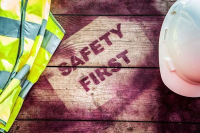 spray painted wood says safety first with yellow safety vest and hard hat