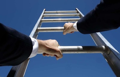 Close up of a male's business suit covered arms and white hands grasping a ladder pointed towards a clear blue sky