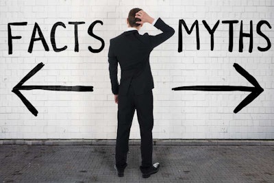Man in black dress suit facing a white bricck wall standing on black brick road with the word facts written on on the wall to the left of the man with an arrow pointing left and the word myths on the right side of the wall with a right arrow under the wor