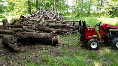 tractor pulling a bunch of chopped down trees