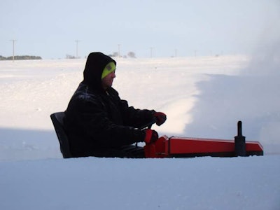 man driving a red tractor in a large amount of snow