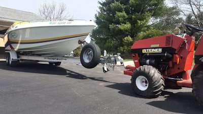Red Tractor towing a Big white speed boat