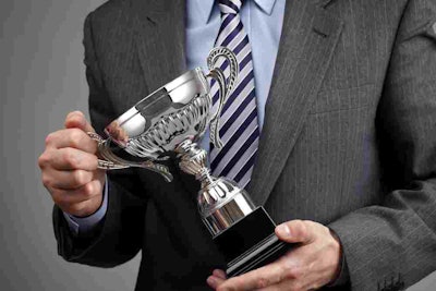 Man in suit holding silver trophy
