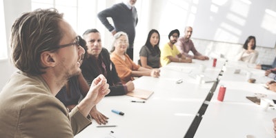 People holding a meeting around a white rectangular table