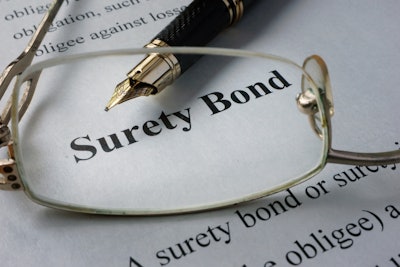 Eye glasses and fountain pen on top of paperwork discussing surety bonds
