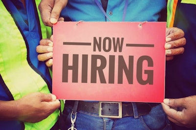 Workers holding Now Hiring sign