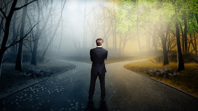 Business man standing at a fork in the road