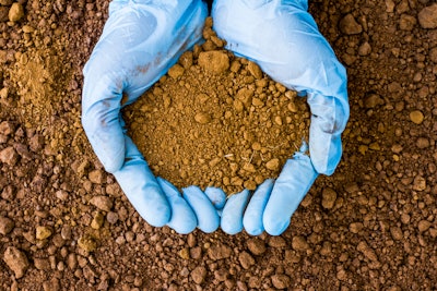 Gloved hands holding soil