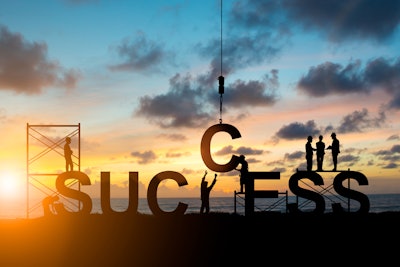 Workers constructing a sign that reads success