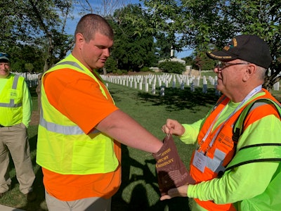Desert Storm veteran Dan Smalt (right) hands out coins to his veteran and active-duty crew members. Photo: Beth Hyatt/Total Landscape Care