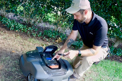 Brian Chapman, directors of fleet and facilities, demonstrates how easy it is to operate the Husqvarna Automower. Photo: Beth Hyatt/Total Landscape Care