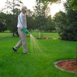 A landscaper spraying herbicide on a lawn