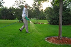 A landscaper spraying herbicide on a lawn