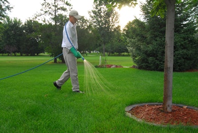 A landscaper spraying herbicide on a lawn