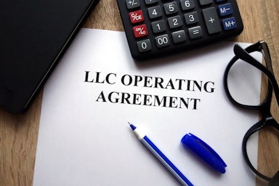LLC Operating agreement on desk with pen, glasses, and calculator