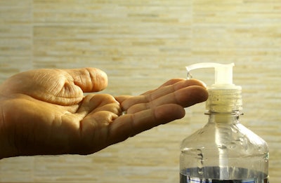 A hand receiving a drop of hand sanitizer