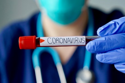 medical professional hold vial of blood with 'CORONAVIRUS' written on it