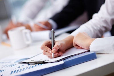 hand holding pen and writing on paper on clipboard during a training session