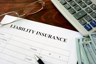 liability insurance form on desk surrounded by glasses, calculator, and stack of money