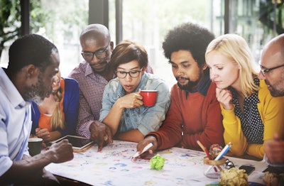 colleagues gather around off desk to collaborate on project