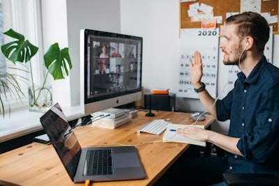 man sitting at home office desk on a on video conference with colleagues