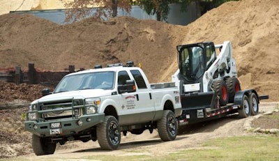 pickup truck with weight distribution hitch towing bobcat skid steer