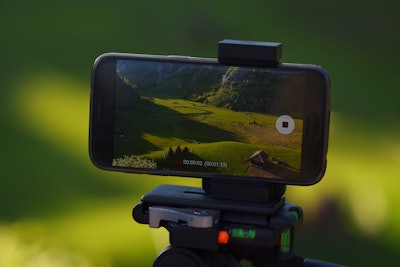 cell phone on leveling base tripod capturing scenic video