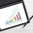a colorful upward trending bar graph on paper with a pen