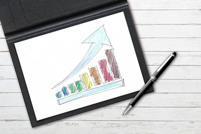 a colorful upward trending bar graph on paper with a pen