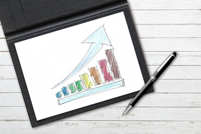 a colorful upward trending bar graph on paper with a pen