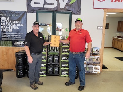 ASV and Duffy Sales and Rental associate holding the 2020 ASV Dealer of the Year award in shop