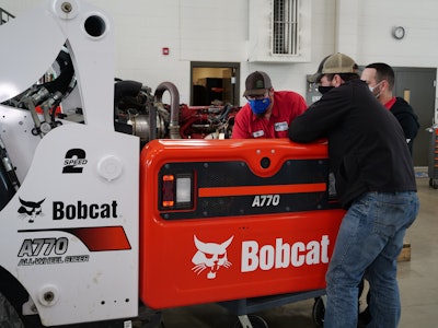 Diesel technicians working on a Bobcat A770 All-Wheel Steer indoors