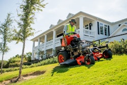 A landscaper cutting grass with a Kubota SZ Series commercial stand-on mower