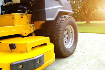 A yellow riding lawn mower parked on a driveway